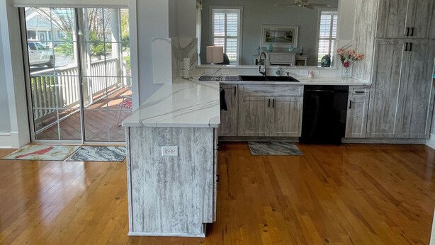 A modern kitchen with wooden cabinets, a marble countertop, and a built-in dishwasher.