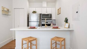 A modern kitchen with white cabinetry, stainless steel appliances, and a central island with stools.