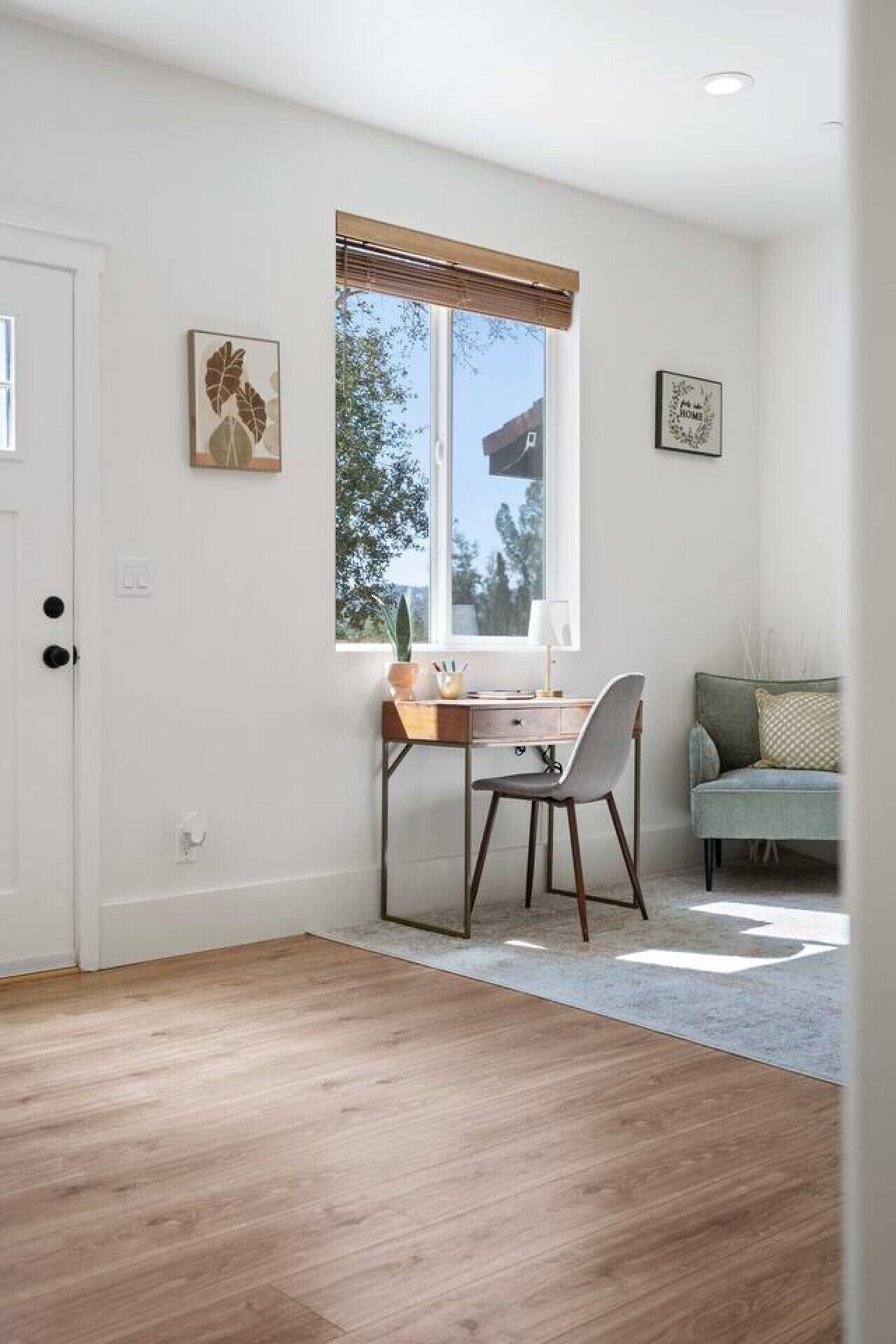 Une pièce comprenant un bureau, une chaise et une fenêtre avec des stores.
