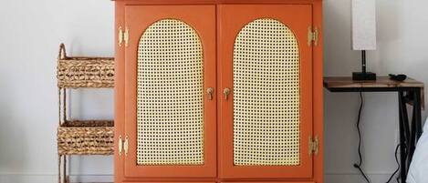 Ein Zimmer mit einem roten Schrank, Korbwannen, einem Globus und einem gerahmten Bild an der Wand.