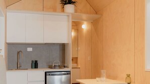 A compact kitchen with white cabinets, a stainless steel dishwasher, and a small dining table.