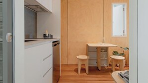 A compact kitchen with wooden cabinets, a small dining table, and stools.