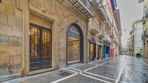 A cobblestone street with a building featuring a large arched entrance labeled "Re-Read" and a visible storefront named "DUNZEL." - "Pamplona center suites" luxury Apartment city center (Pamplona)