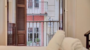 A room with a bed, a window with a view of a red brick building and a balcony. - "Pamplona center suites" luxury Apartment city center (Pamplona)