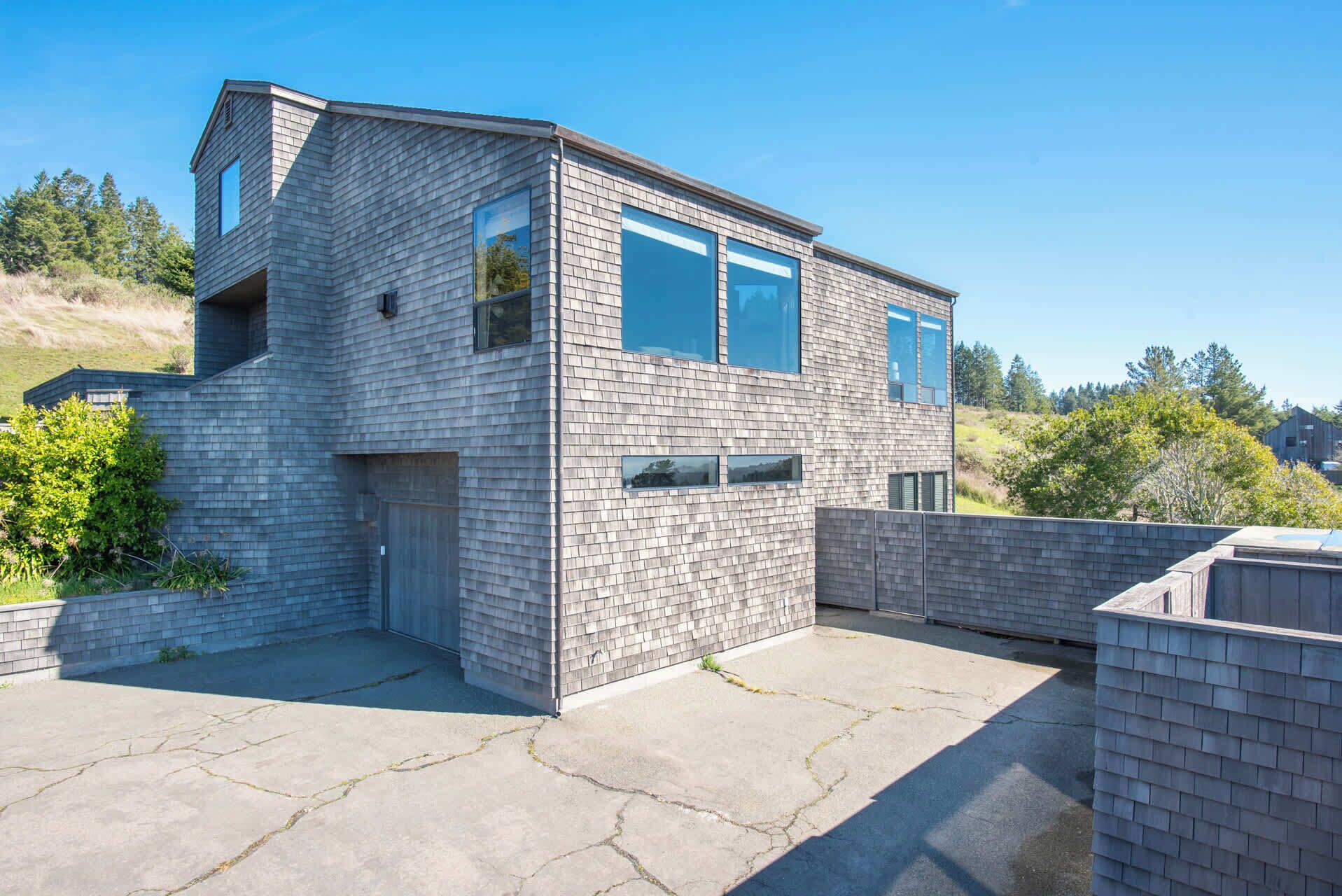 Ein modernes, zweistöckiges Haus mit Ziegelaußenwand, großen Fenstern und einer Garage.