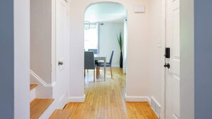 A hallway with wooden flooring, white walls, and a dining area with a table and chairs. - Spacious 4 bedroom home with large yard (Wayland)