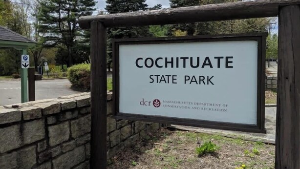 A sign for Cochituate State Park with a stone wall and trees in the background. - Spacious 4 bedroom home with large yard (Wayland)