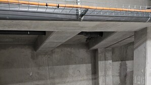 Un estacionamiento vacío con paredes de concreto, un espacio reservado para discapacitados con señalización azul y líneas de estacionamiento blancas.