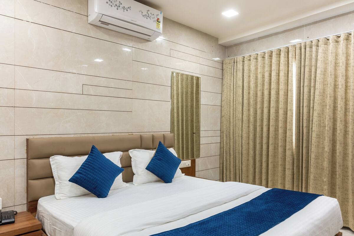 A modern hotel room with a large bed, a nightstand, a ceiling fan, and an air conditioning unit.