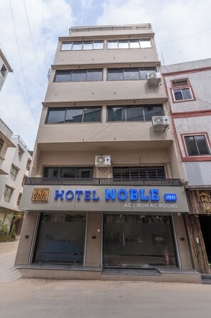 A multi-story building with a sign for Hotel Noble Inn, indicating both AC and non-AC rooms. - Hotel Noble Inn (Ahmedabad)