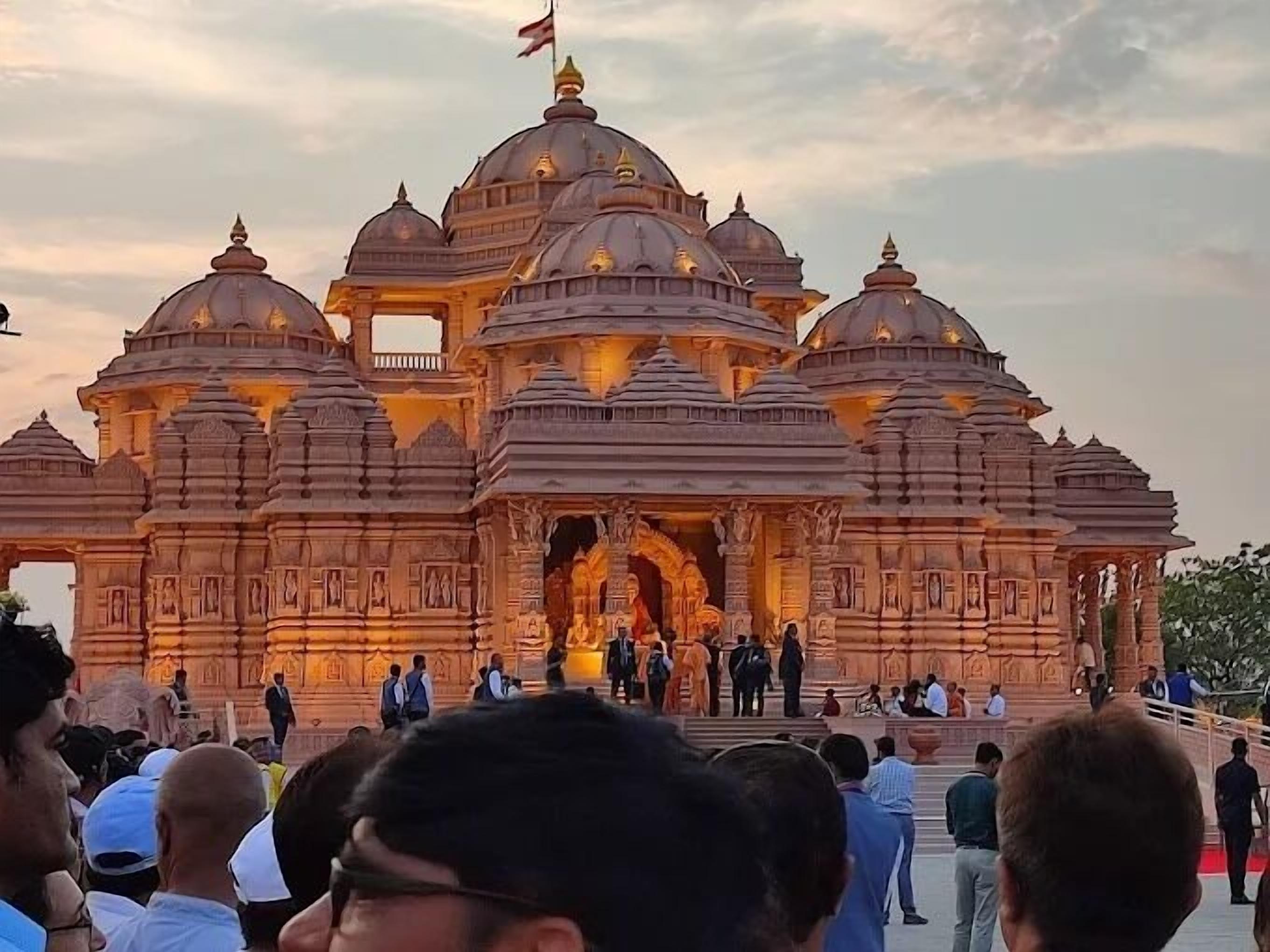 A large, ornate temple with multiple domes and intricate carvings, surrounded by a crowd of visitors.