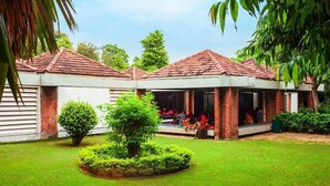 A courtyard with two brick buildings, a central garden, and a covered seating area. - Hotel Noble Inn (Ahmedabad)