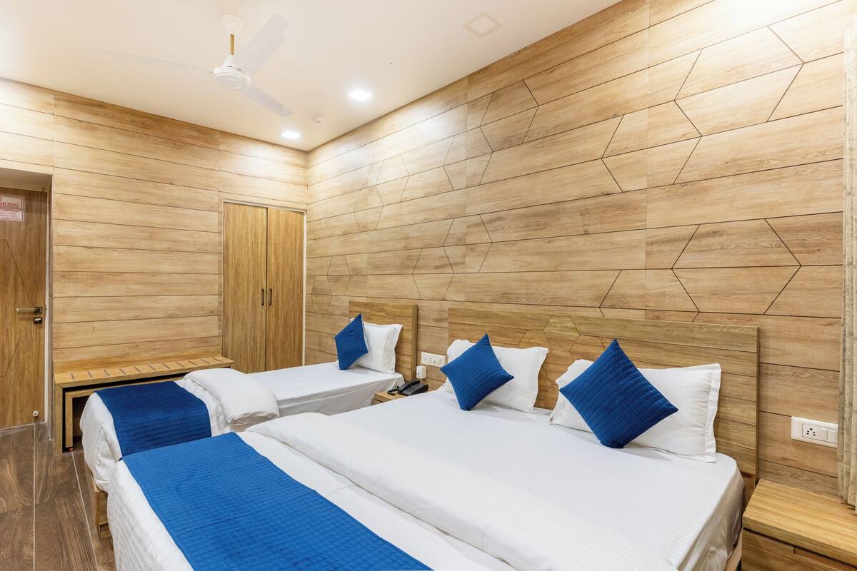 A hotel room with two beds, wooden panel walls, a ceiling fan, and a door with a sign.