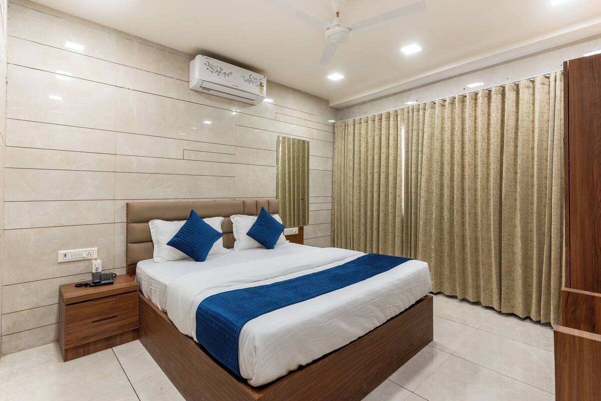 A modern hotel room with a large bed, a nightstand, a ceiling fan, and a window with curtains.