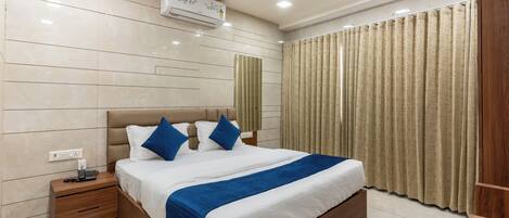 A modern hotel room with a large bed, a nightstand, a ceiling fan, and a window with curtains.