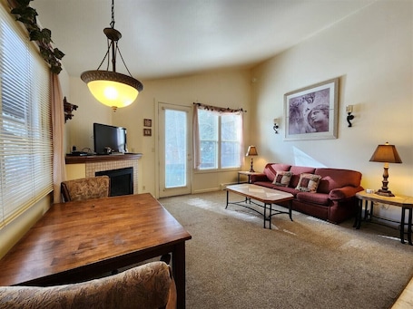 A living room with a wooden dining table, a red sofa, a coffee table, and a television.