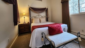 Une chambre à coucher avec un lit, une table de chevet, une lampe et une fenêtre avec des rideaux.