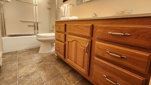 A bathroom with a shower, toilet, and wooden vanity with drawers. - Fall River Overlook 202- With Seasonal Pool Access plus RMNP Entrance Close By! (Estes Park)