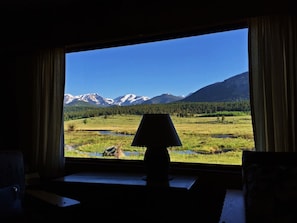 Una habitación con un ventanal grande que ofrece vistas a un paisaje montañoso y un campo cubierto de hierba.