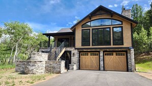 A two-story house with a stone facade, large windows, and a garage with wooden doors.