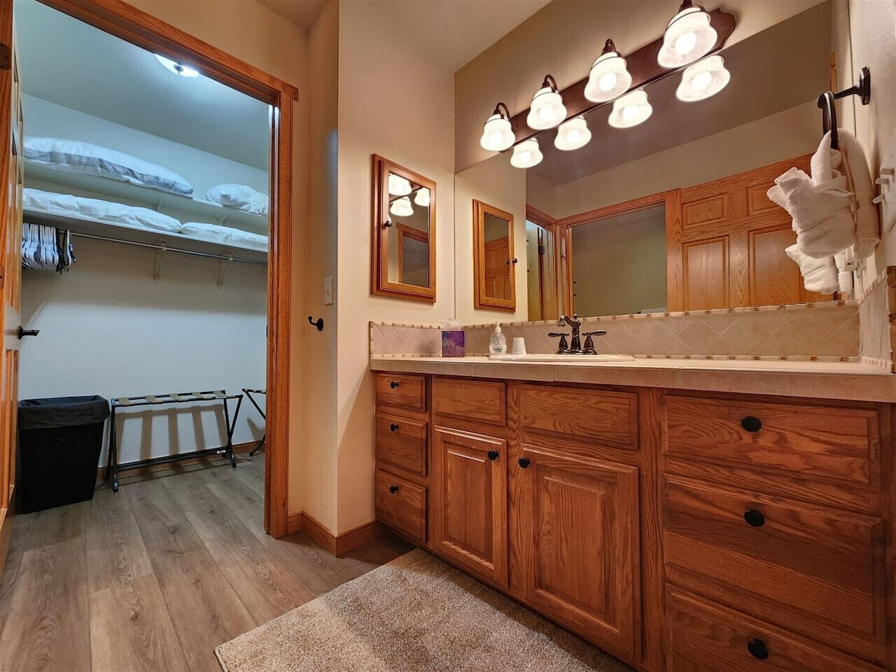 A bathroom with wooden cabinets, a vanity with a mirror, and a light fixture above the mirror.