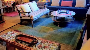 A cozy living room with a sofa, armchair, and coffee table, a bookshelf, and a dining area with a table and chairs. - Bobcat`s Casita- Primal Serene Surroundings, Nearby Lake Estes, 9 and 18 hole golf, Stanley Hotel! (Estes Park)