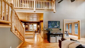 A spacious interior with a wooden staircase, a dining area, and a view through a glass door.