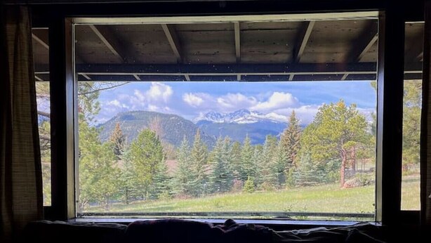 Una habitación con un ventanal grande que da a un paisaje montañoso.