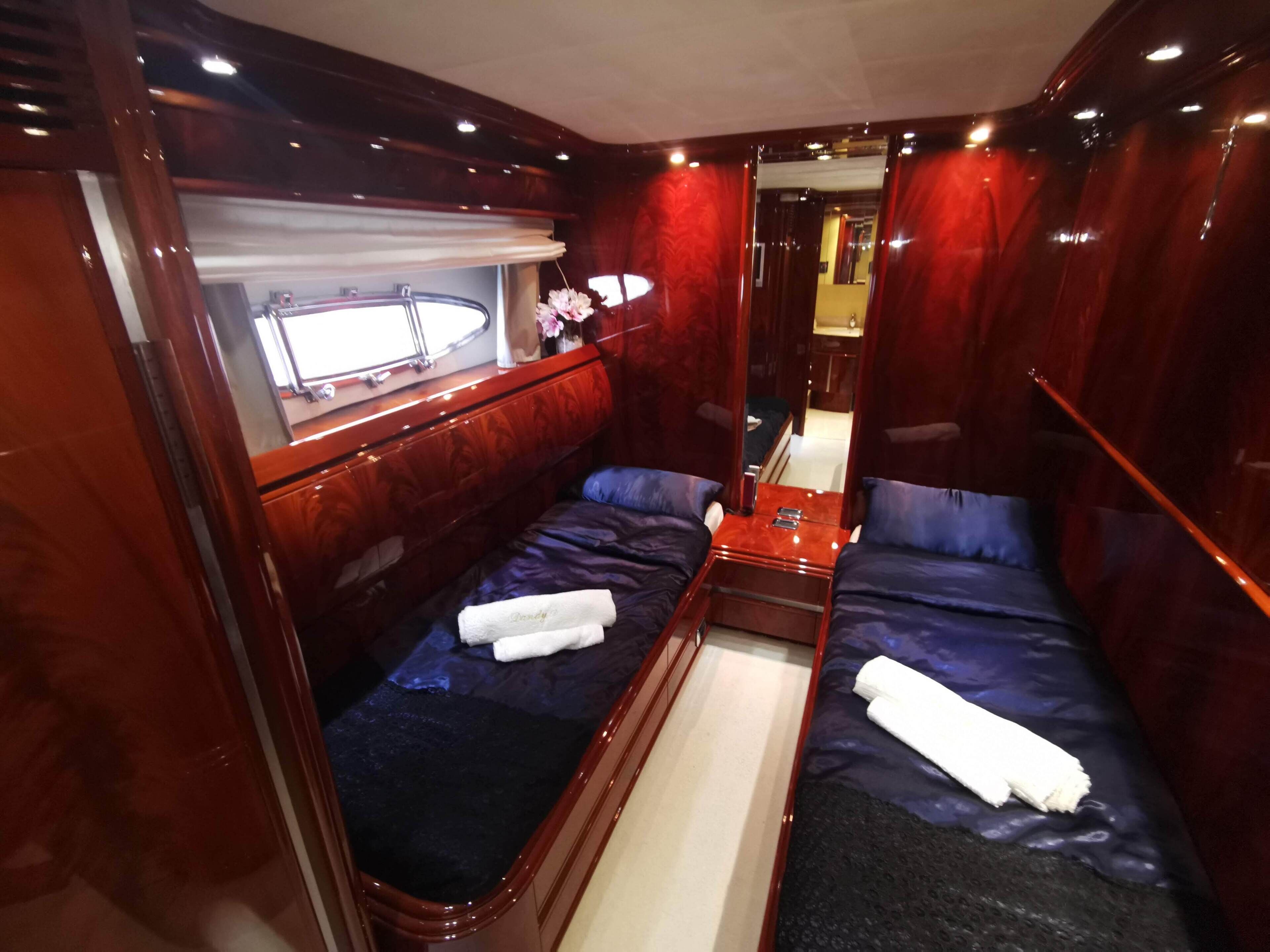 A compact, well-lit cabin with two beds, a small table, and a mirror.