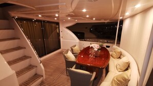 Ein Yacht-Interieur mit einem Essbereich, der einen Holztisch, Korbstühle und eine gepolsterte Bank umfasst.