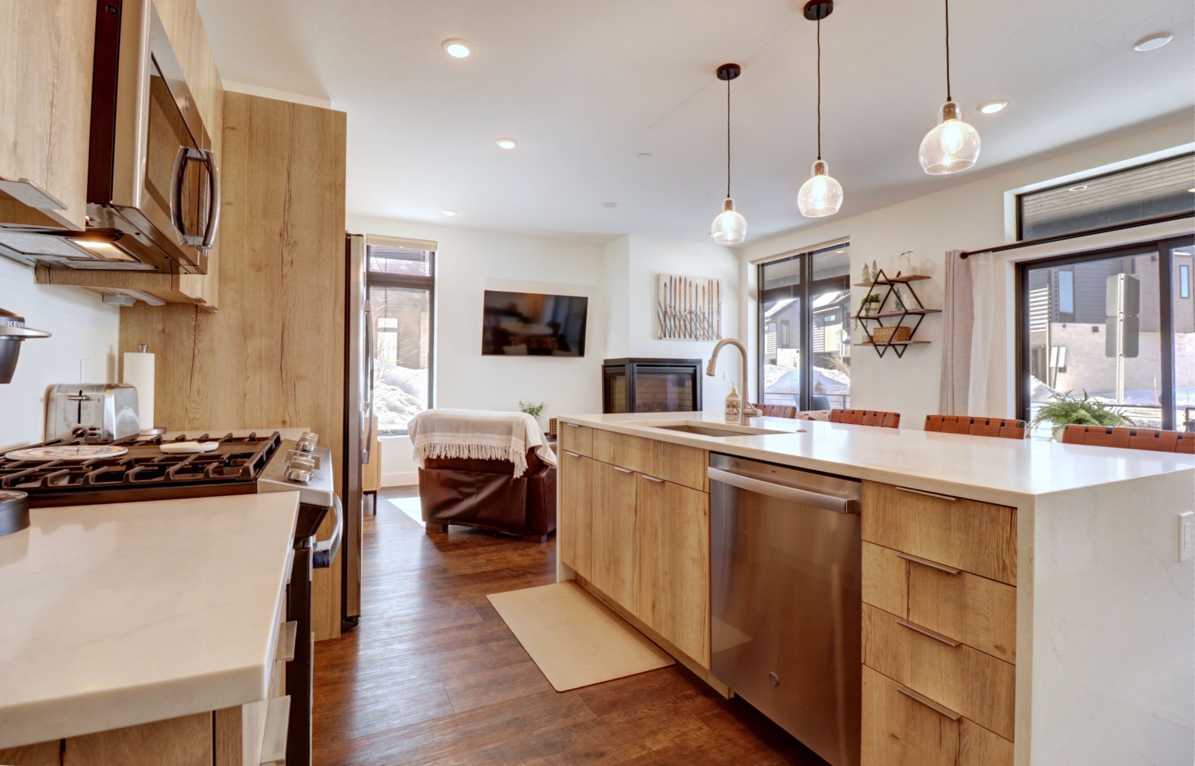Una cocina moderna con armarios de madera, electrodomésticos de acero inoxidable e iluminación colgante.