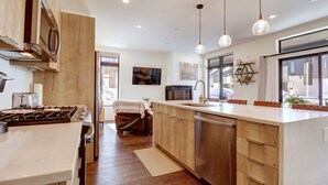 A modern kitchen with wooden cabinets, stainless steel appliances, and pendant lighting. - River West 515 2 Bedroom Condo (Silverthorne)