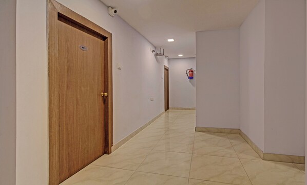 A hallway with a wooden door marked '405', a fire extinguisher, and a ceiling-mounted security camera. - HOTEL ROYAL CROWNE (Barakpur)