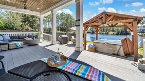 Une terrasse extérieure couverte, aménagée avec des sièges, un jacuzzi et offrant une vue sur un lac.