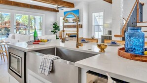 Une cuisine moderne dotée d’un grand îlot central, d’appareils électroménagers en acier inoxydable et d’un plafond en bois.