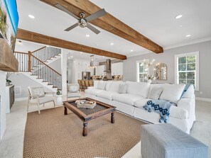 A spacious living room with a white sofa, a wooden coffee table, and a staircase leading to an upper level.