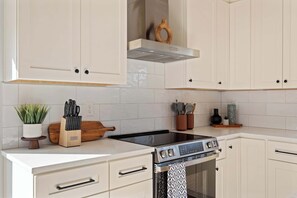 A modern kitchen with white cabinetry, a black stovetop, and a built-in oven.