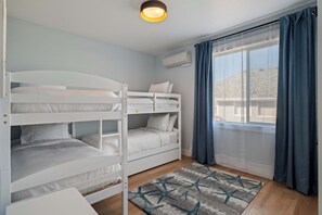 Ein Zimmer mit Etagenbetten, einem fenster mit Vorhängen und einer Deckenleuchte.