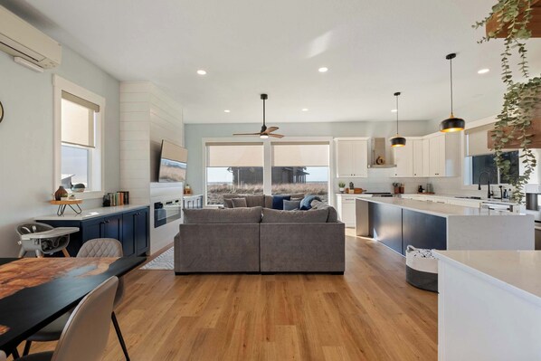 A modern kitchen with a central island, white cabinetry, and a view to the outdoors.