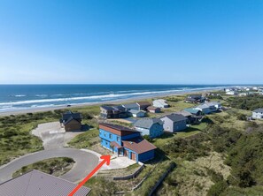 A coastal residential area with houses, a beach, and a clear sky.