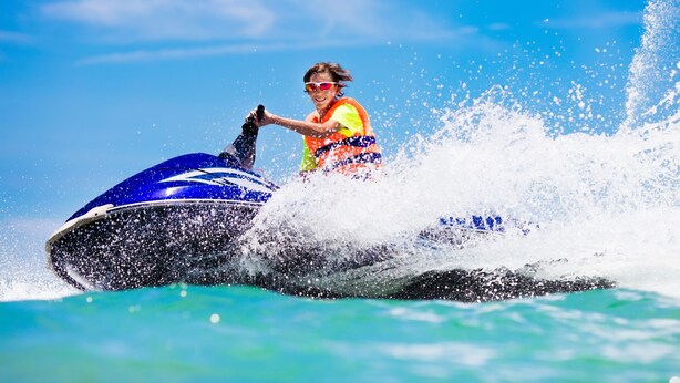 Eine Person fährt mit einem Jetski über klares Wasser.