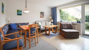 Un salon comprenant un canapé, des fauteuils, une table et une fenêtre donnant sur un paysage verdoyant.
