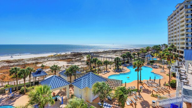 A resort with a pool, beach, and palm trees.