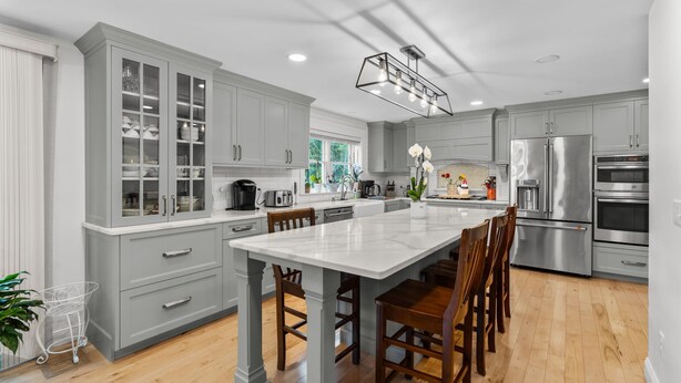 A modern kitchen with grey cabinetry, a central island, and stainless steel appliances.
