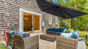 A patio with wicker furniture, a sliding glass door, and a large umbrella.