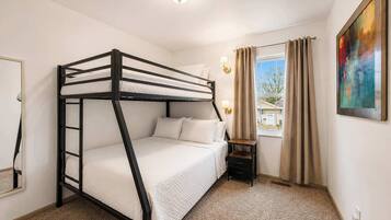 A bunk bed room with a window, a nightstand, and a painting on the wall.
