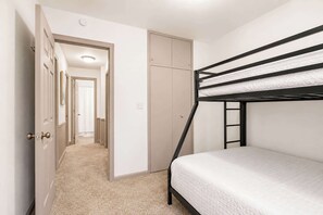 Habitación con literas, una puerta que da a un pasillo y un armario.