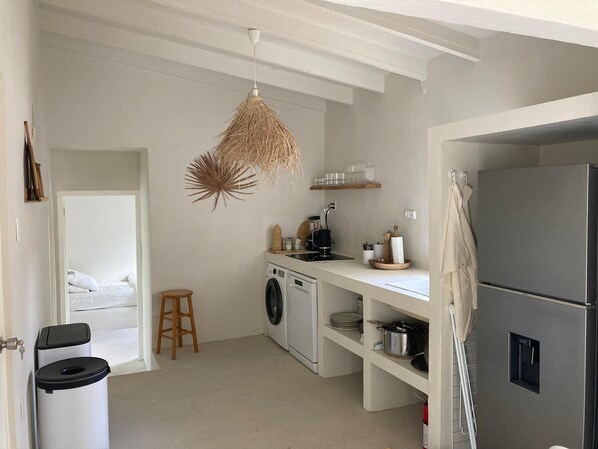 A compact kitchen with a washing machine, a refrigerator, and a hanging light fixture.