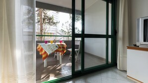 A room with a sliding glass door leading to an outdoor balcony with a table and chairs. - Warm and Bright Apartment in Bibione Near the sea (San Michele al Tagliamento)