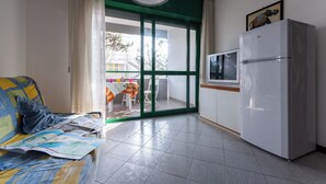 A living room with a sofa, a television, and a refrigerator. - Warm and Bright Apartment in Bibione Near the sea (San Michele al Tagliamento)